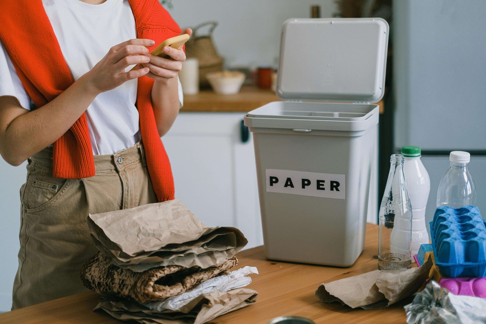 Person sorting recyclables in a modern minimalist kitchen scaled